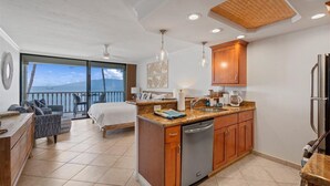 Una cocina moderna con armarios de madera, lavavajillas y un ventanal con vistas a un balcón.