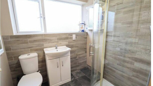A bathroom with a toilet, sink, and glass shower enclosure. - Home in Milton Keynes (Milton Keynes)