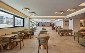 A modern restaurant interior with a central counter, multiple seating areas, and a view through large windows. - Enorme Epavli Urban Living (Hersonissos)