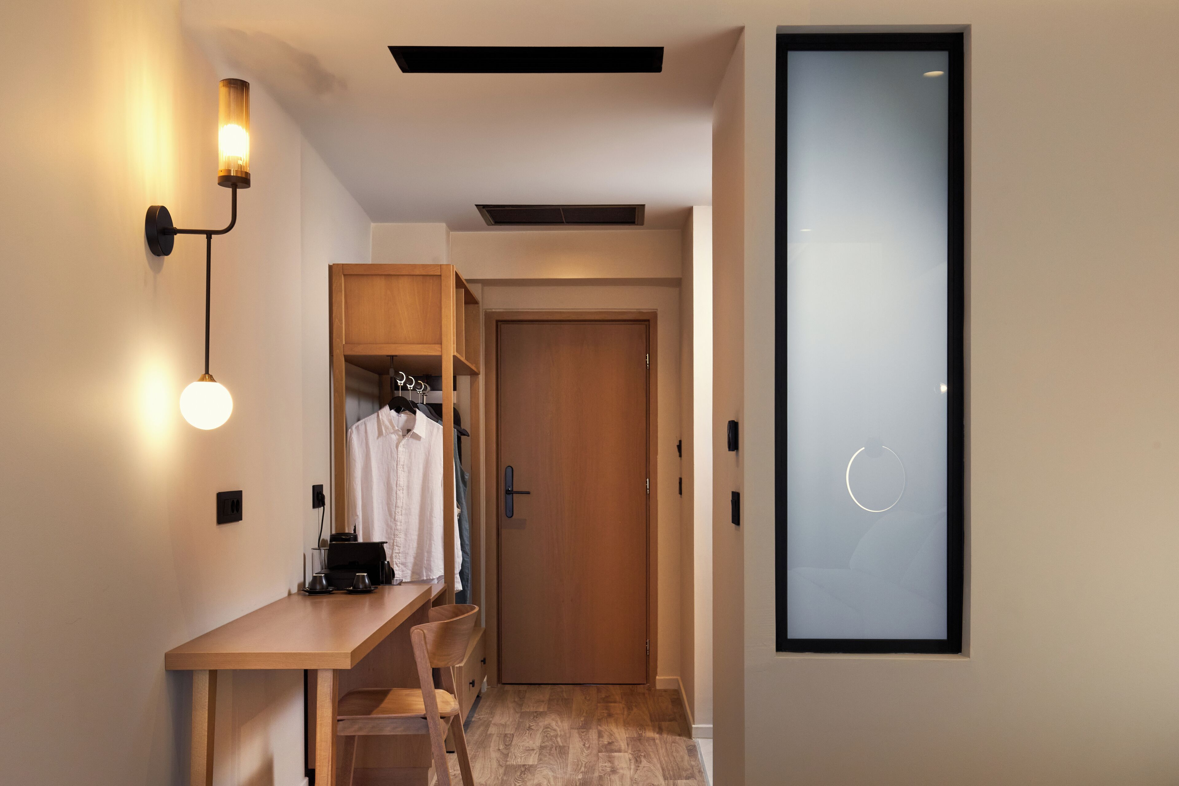 A hallway with a wooden desk, a wardrobe, and a door with a frosted glass panel.
