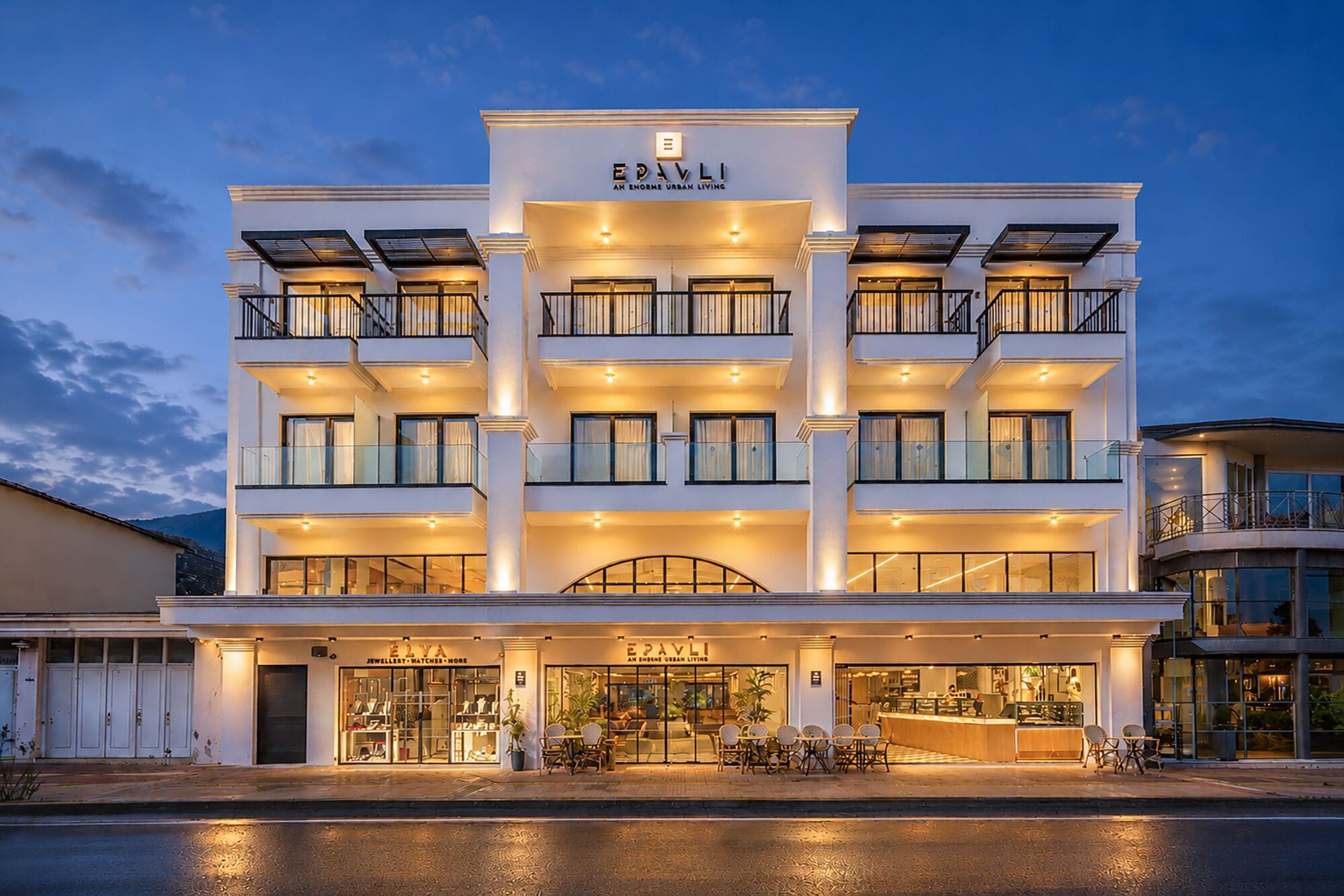 A multi-story hotel with a modern facade, balconies, and a ground-level shop.