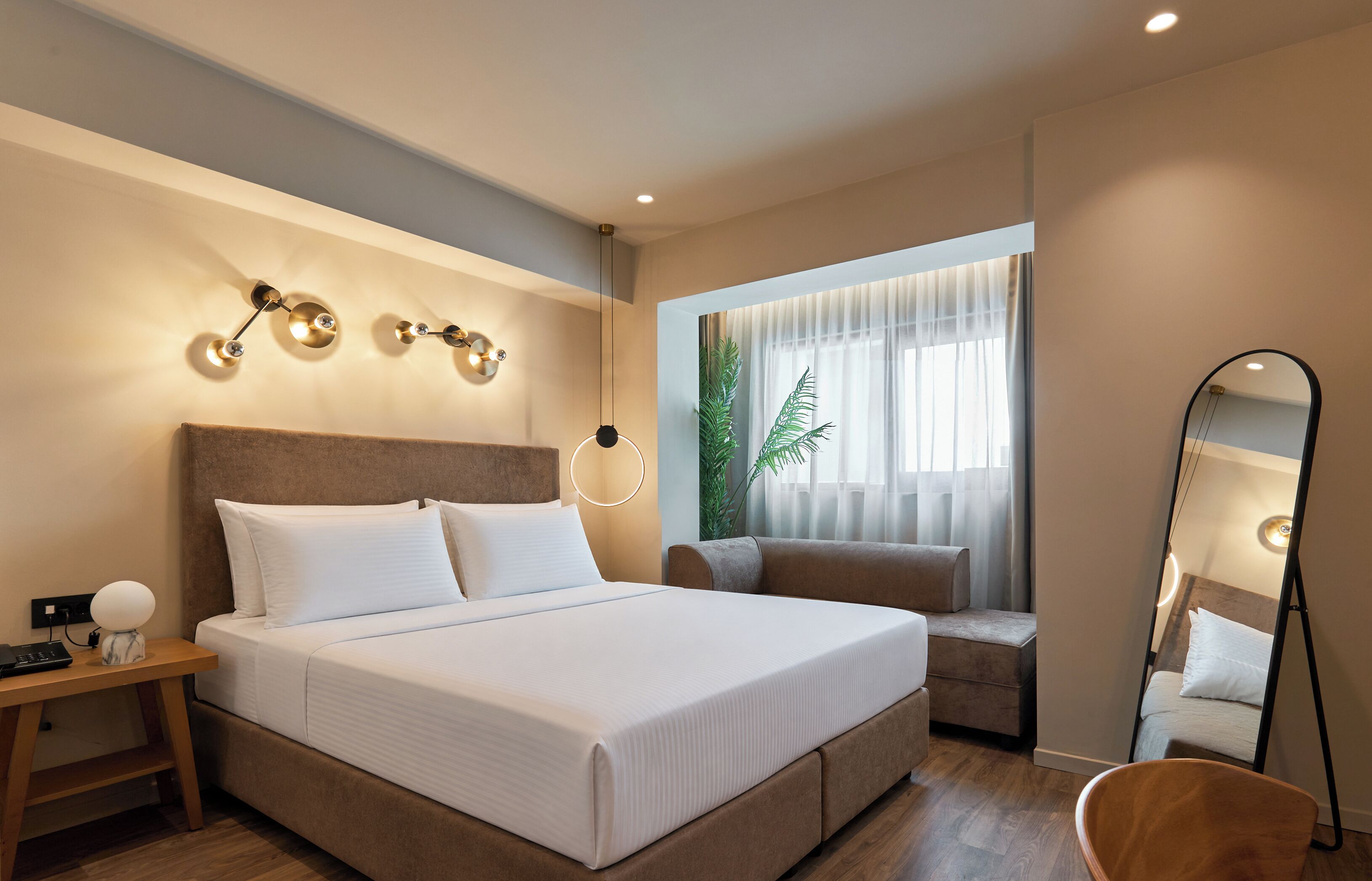 Een moderne hotelkamer met een groot bed, nachtkastje, lamp en een spiegel.