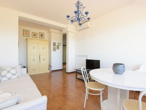 A room with a bed, a dining table with chairs, a television, and a cabinet. - Montparnasse by Interhome (Punta Ala)