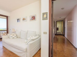 A room with a white sofa, a lamp, and framed pictures on the wall. - Montparnasse by Interhome (Punta Ala)