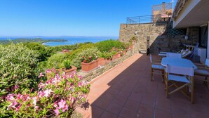 Une terrasse avec vue sur la mer, des murs en pierre et des plantes en pot.