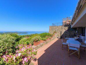 A terrace with a view of the sea, stone walls, and potted plants. - Montparnasse by Interhome (Punta Ala)