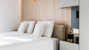 A modern bedroom with a wooden headboard, a large bed with white bedding, and a bedside table with a decorative globe.