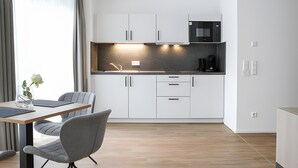 Una cucina moderna con mobili bianchi, un forno a microonde integrato e una macchina per il caffè.