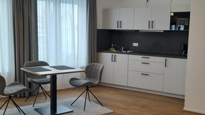 Eine moderne Küche mit weißen Schränken, einer schwarzen Arbeitsplatte und einem Essbereich mit Tisch und Stühlen.