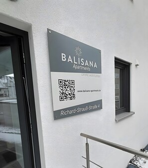A sign for Balisana Apartments with a QR code and address.