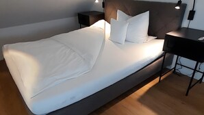 Ett modernt sovrum med en stor säng, två sängbord och ett skrivbord med en lampa.