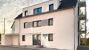 En modern byggnad med ett platt tak, flera fönster och en skylt som visar att det är ett hotell.