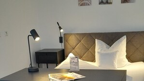 A neatly arranged hotel room with a bed, a desk with a chair, a nightstand, and a lamp. - Apartment 'Apparment 4' with Wi-Fi (Balingen)