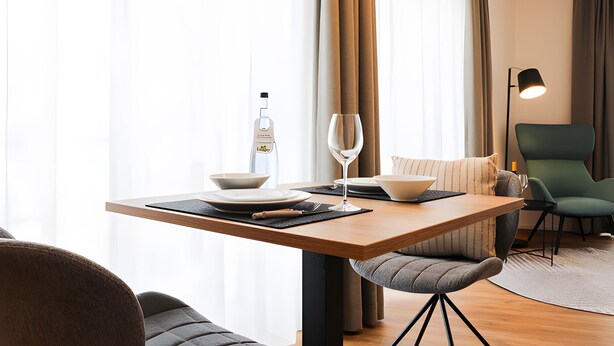 A modern dining area with a wooden table, a wine glass, a bottle, and a bowl. - Apartment 'Apparment 4' with Wi-Fi (Balingen)