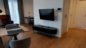 A modern living room with a flat-screen TV, a wooden dining table, and a sofa. - Apartment 'Apparment 4' with Wi-Fi (Balingen)