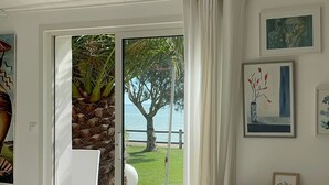 Una stanza con un letto, una scrivania e vista su un albero e l'acqua.