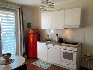 A compact kitchen with white cabinets, a red refrigerator, a sink, and a small countertop. - Quiet Garden Studio near Como (Lurate Caccivio)