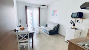 A modern kitchen with a dining area, a gray sofa, and a microwave on a shelf. - Vinko in Rovinj - Istrien / Vinko in Rovinj - Appartement für 2-3 Personen AP2 (Rovinj)
