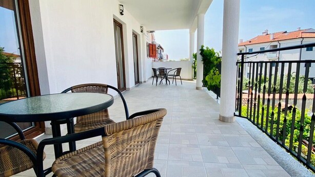 A covered outdoor area with a table and chairs, a view of buildings in the background, and a tiled floor. - Vinko in Rovinj - Istrien / Vinko in Rovinj - Appartement für 2-3 Personen AP2 (Rovinj)