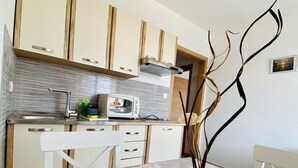 Moderni keittiö, jossa on puiset kaapit, sisäänrakennettu uuni ja ruokapöytä, jonka keskellä on lasinen koriste-esine.