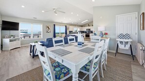 A modern kitchen with white cabinets, a microwave, and a dining area with a white table and blue chairs.