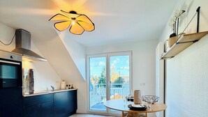 Eine moderne Küche mit Essbereich, ausgestattet mit einem großen Fenster, Holzboden und einer einzigartigen Deckenleuchte.