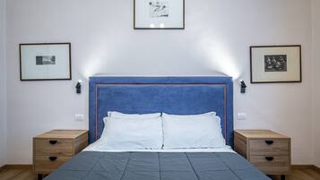 Een slaapkamer met een bed, twee nachtkastjes en drie ingekaderde foto’s aan de muur.