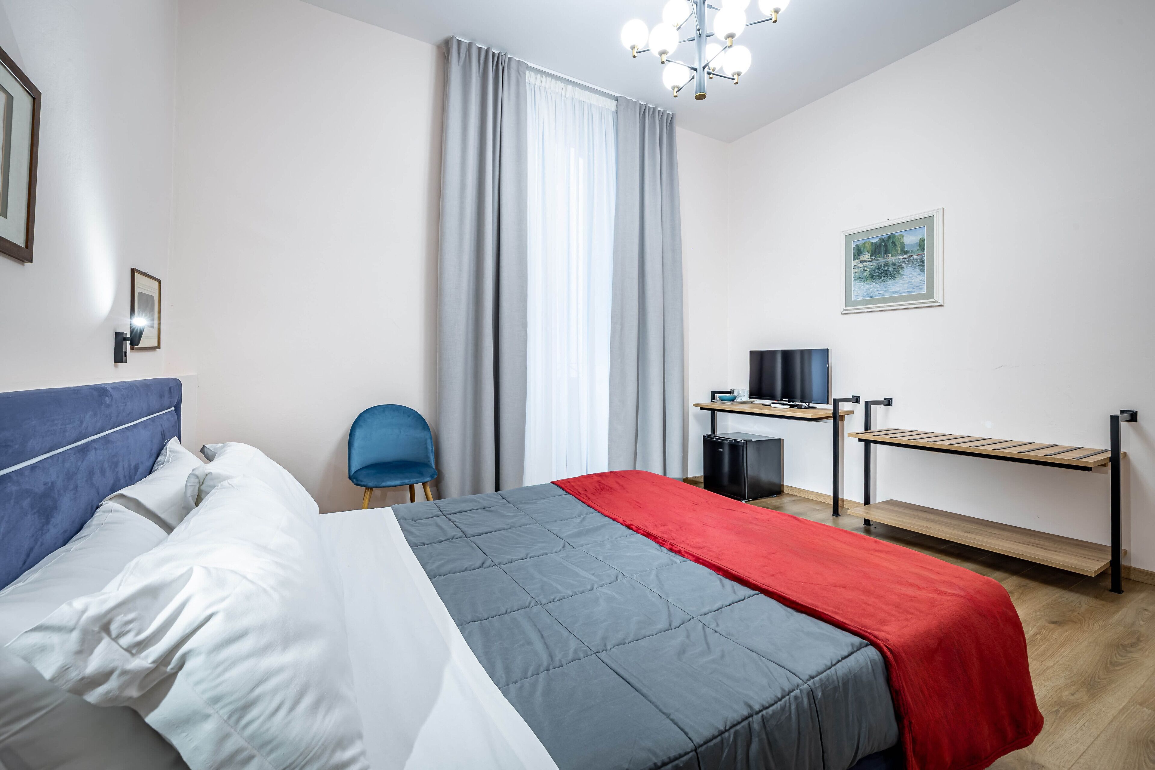 A hotel room with a bed, a desk, a chair, and a TV.
