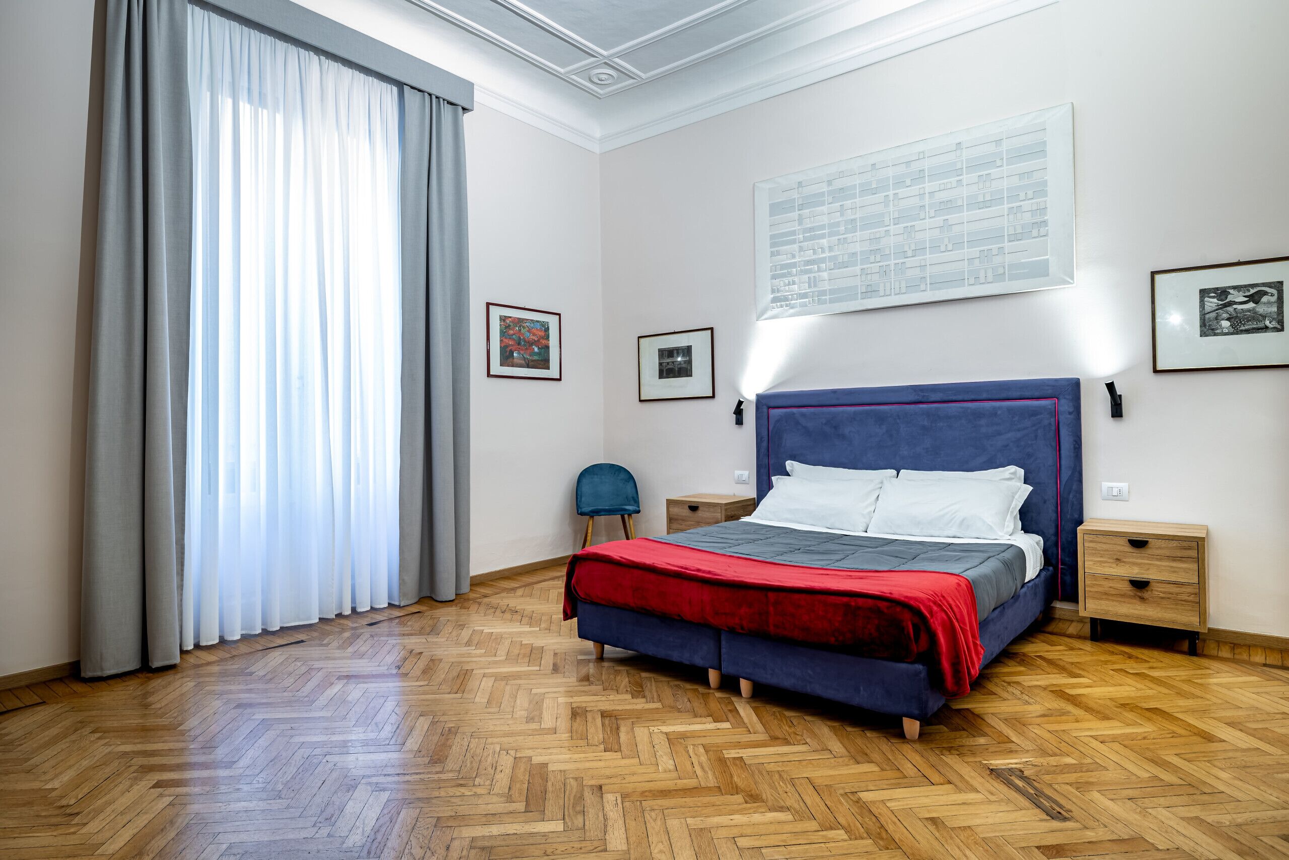 A bedroom with a bed, a chair, a nightstand, and a window with curtains.