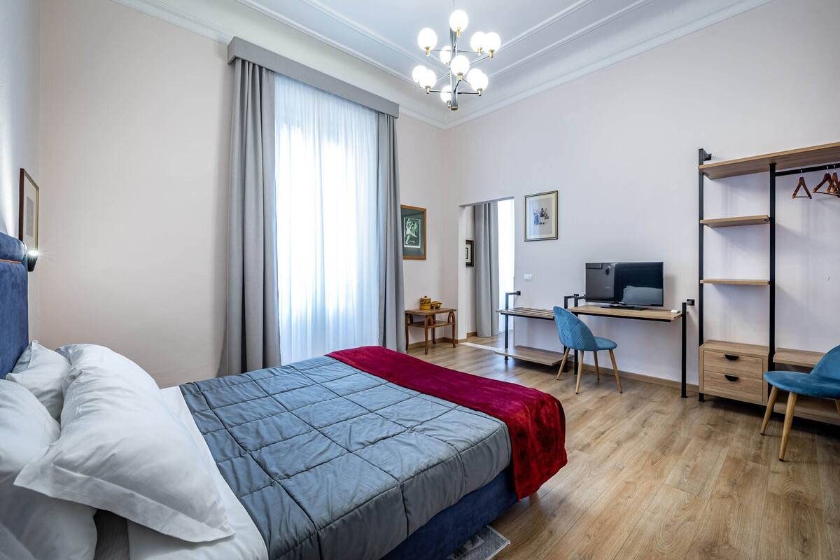 A hotel room with a bed, a desk, a TV, and a wardrobe.