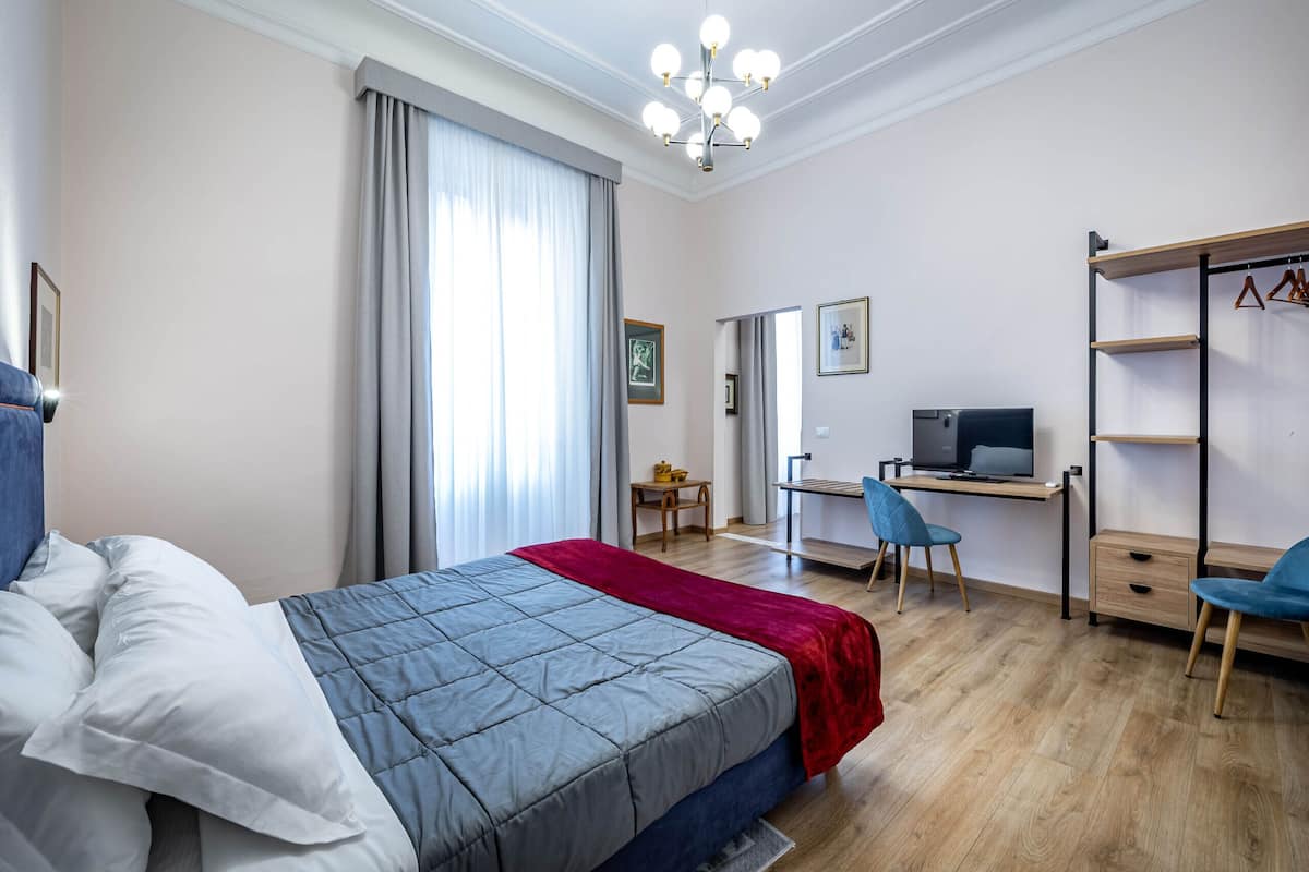 Ein Hotelzimmer mit Bett, Schreibtisch, Fernseher und Kleiderschrank.