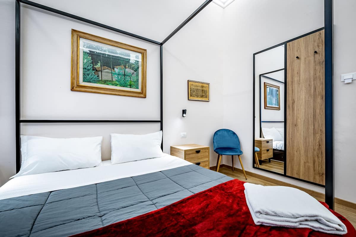 Ein Schlafzimmer mit einem Bett, einem Sessel, einem Kleiderschrank und einem Spiegel.