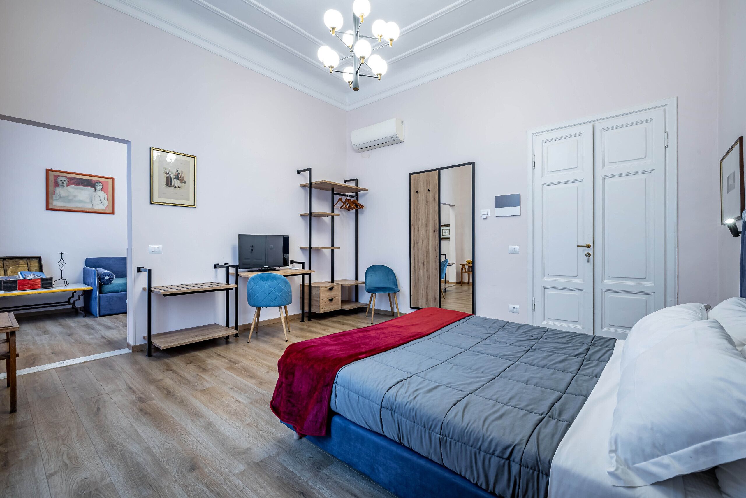 A bedroom with a bed, desk, chair, wardrobe, and a TV.