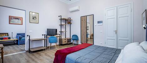 A bedroom with a bed, desk, chair, wardrobe, and a TV.