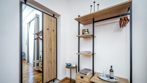 A modern room with a wooden wardrobe, a desk with a chair, and a hanging rack with clothes. - Five Suites Mantellate (Florence)