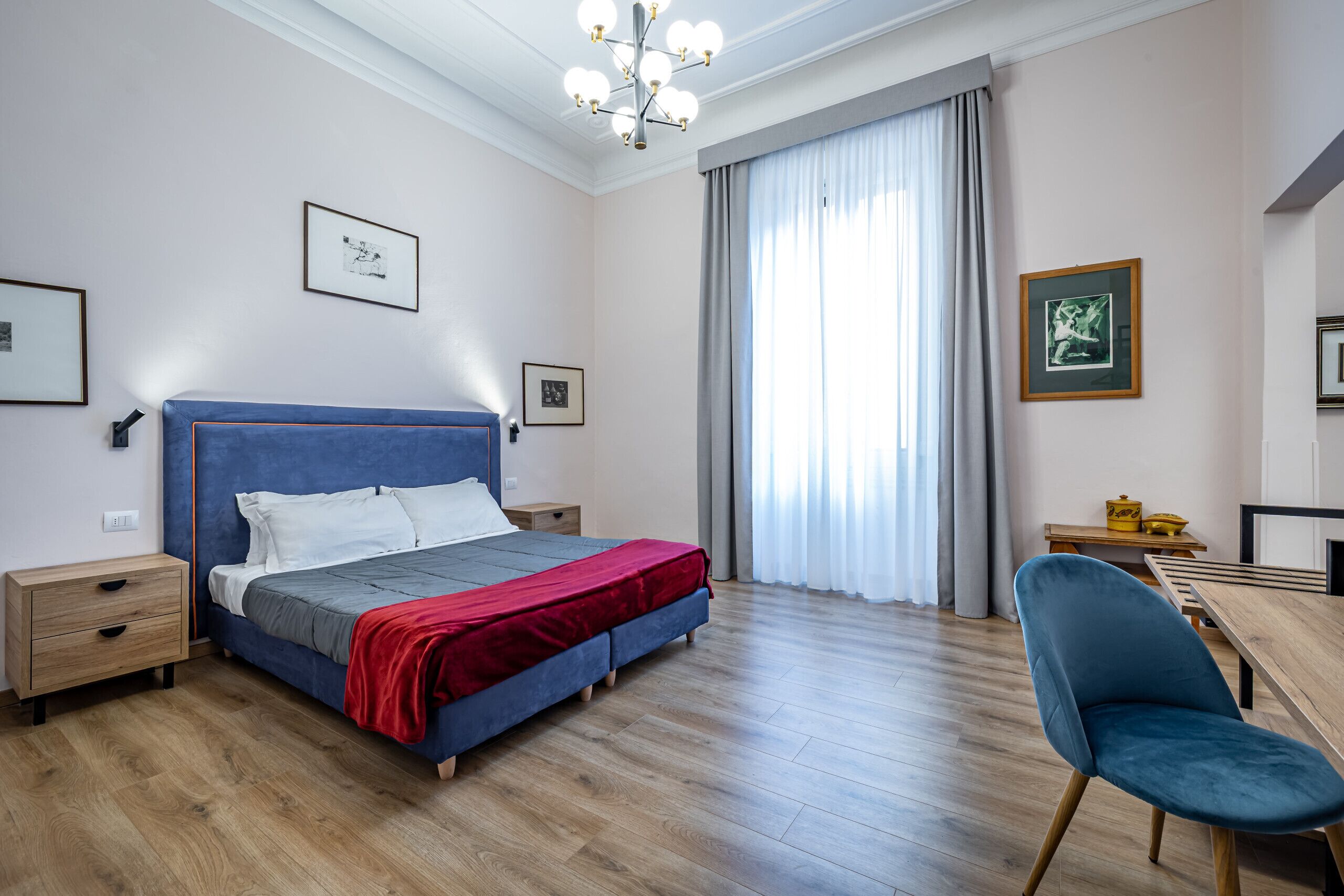 A modern bedroom with a bed, bedside tables, a desk, and a chair.