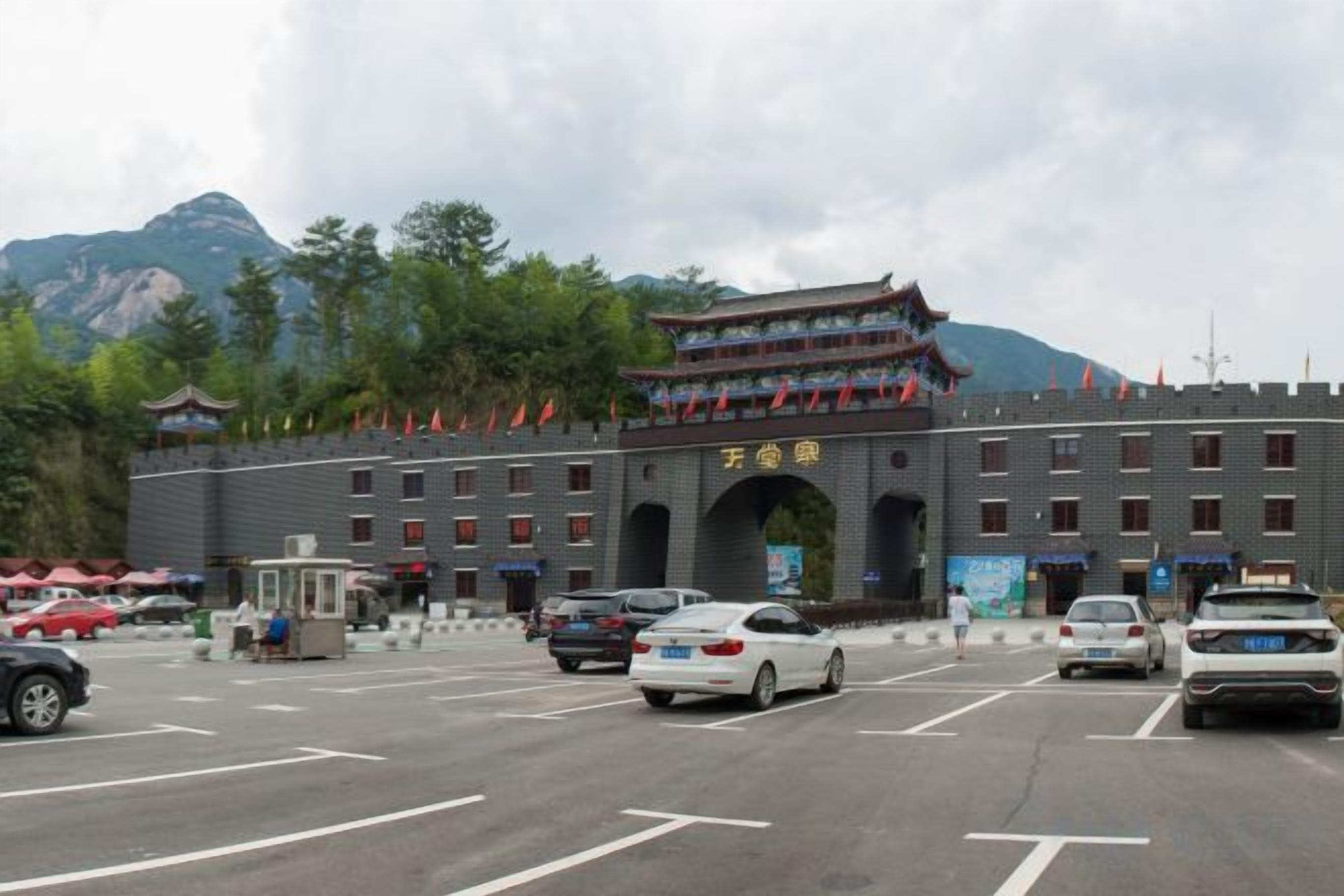 A building with a traditional architectural style, a parking lot, and a mountainous backdrop.