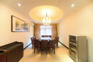 A dining area with a round table, chairs, a chandelier, a painting on the wall, and a cabinet. - Junyi Nanshan Hotel, Luotian (Luotian County)