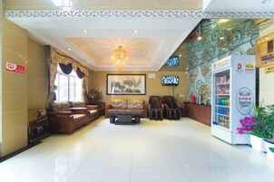 Un hall de hotel con mostrador de recepción, zona de estar y máquina expendedora.
