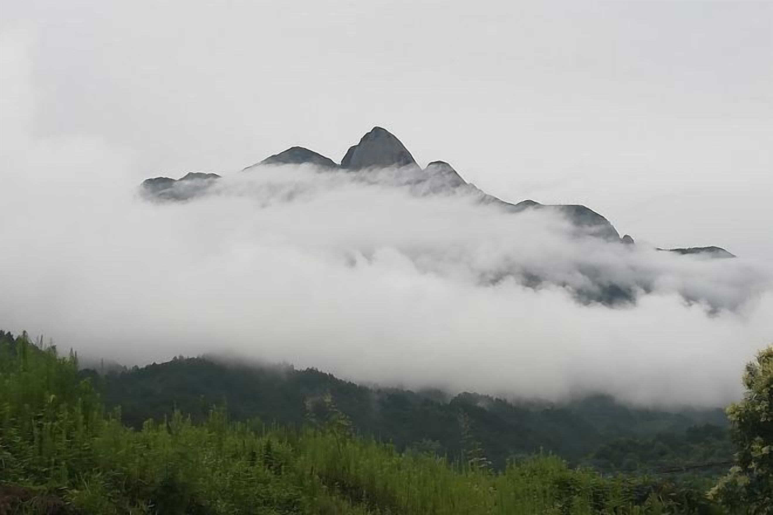 Paisaje montañoso con un pico destacado, parcialmente oculto por nubes.