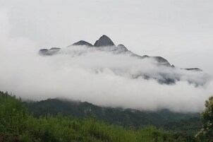 Paisaje montañoso con un pico destacado, parcialmente oculto por nubes.