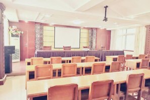 Una sala conferenze con un lungo tavolo, sedie, uno schermo per proiettore e un podio.