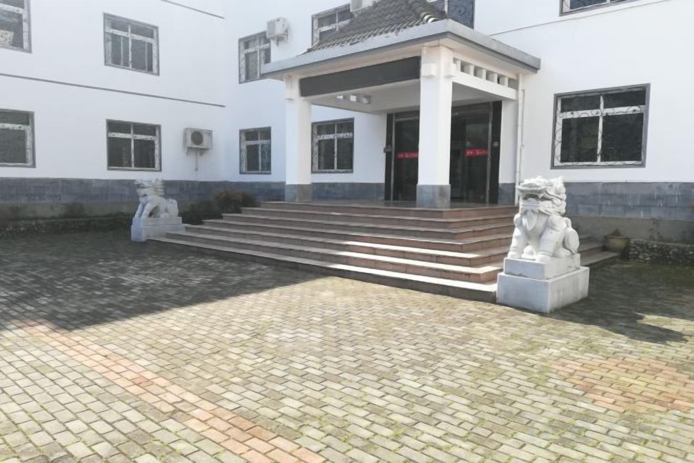 Un edificio con un acceso cubierto y escalones que conducen a él, flanqueado por dos estatuas.