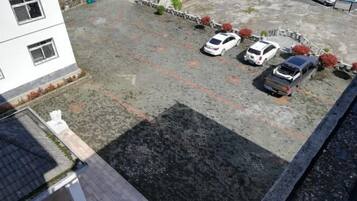 Un estacionamiento con cuatro coches, un edificio con ventanas y suelo pavimentado.