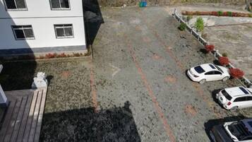 Un estacionamiento con varios autos, un edificio con ventanas y superficie pavimentada.