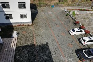Un estacionamiento con varios autos, un edificio con ventanas y superficie pavimentada.