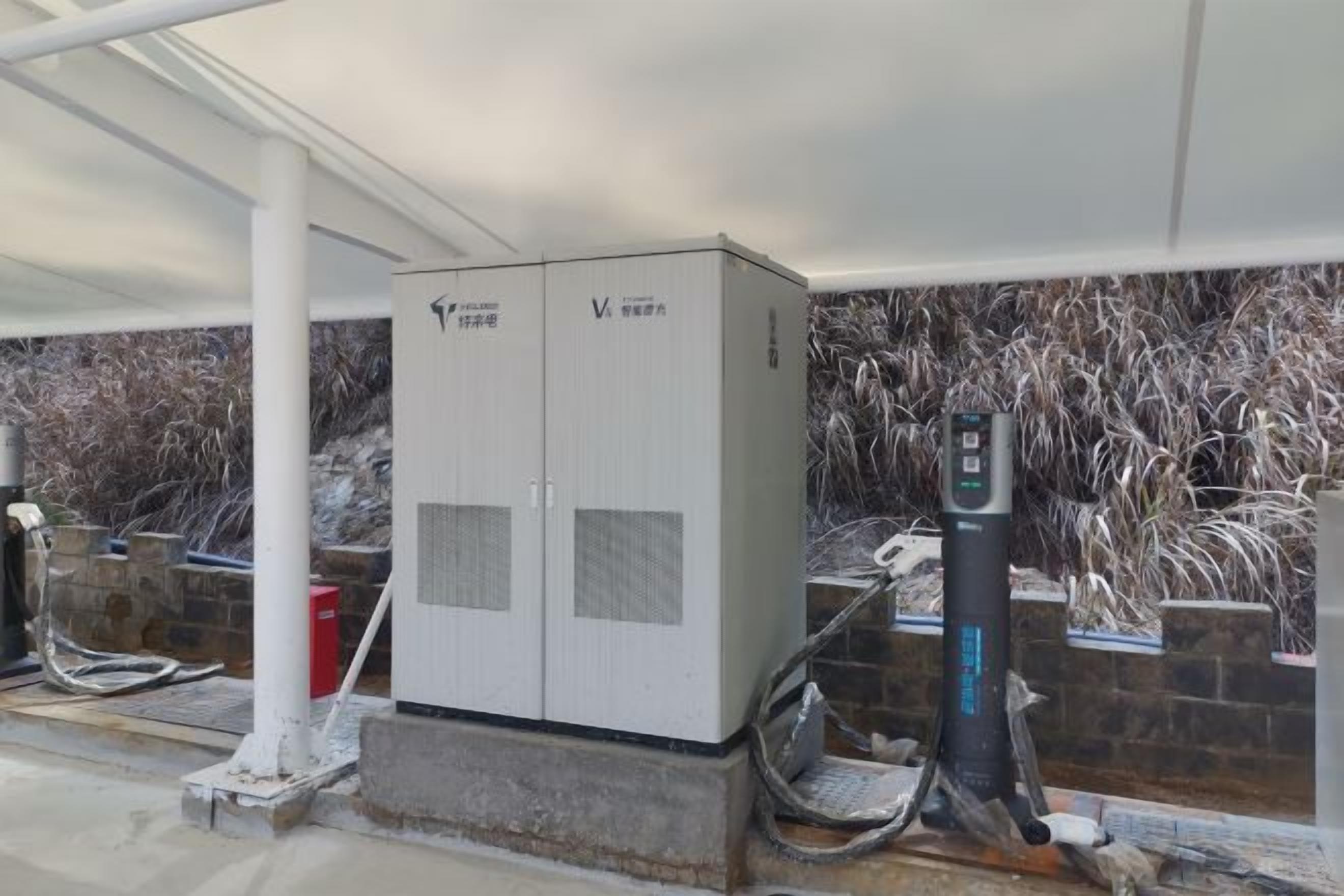 A fuel pump station with a fuel dispenser, a large white cabinet, and a hose reel.