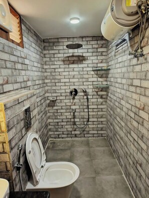 A small, enclosed bathroom with a shower, a toilet, and a sink.