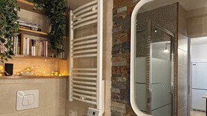 A bathroom with a toilet, a wooden vanity, a mirror, a towel rack, and a shower area.