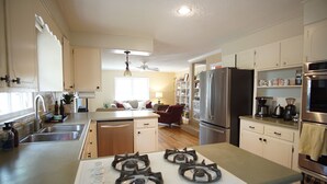 A modern kitchen with a central island, stainless steel appliances, and a dining area with a sofa and table. - Home in North Augusta (North Augusta)